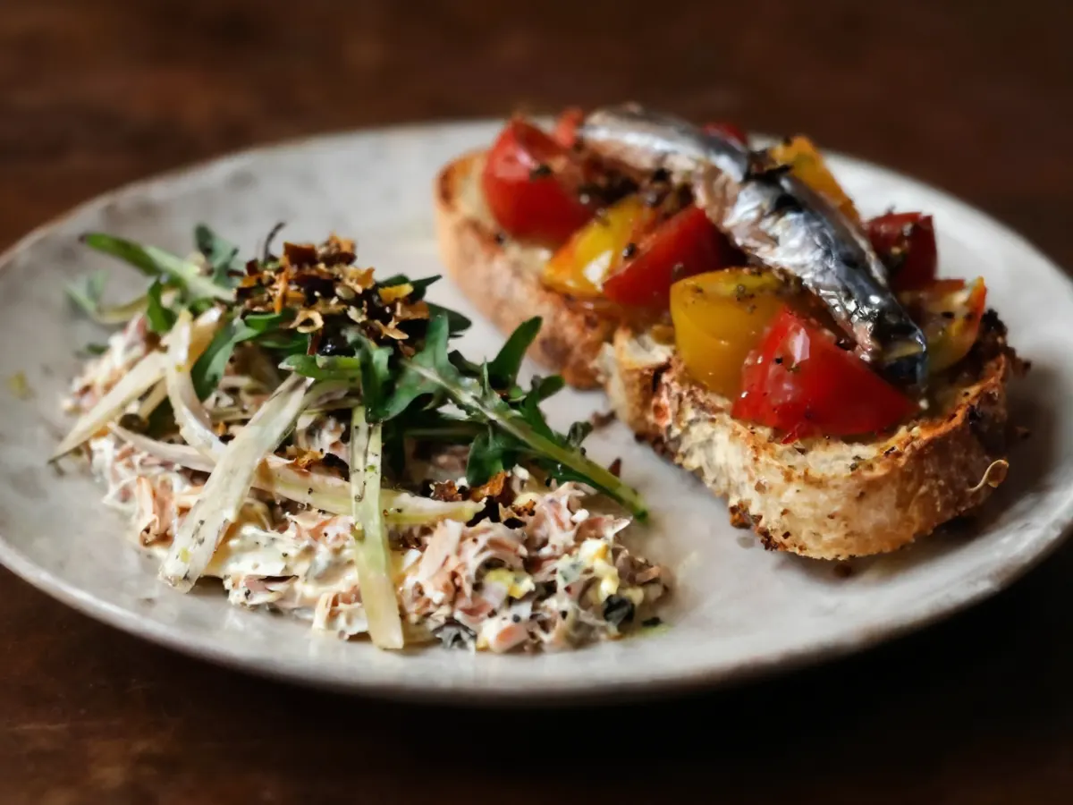 AI-generated photograph: A platter of tuna salad with fennel beside tomato toasts